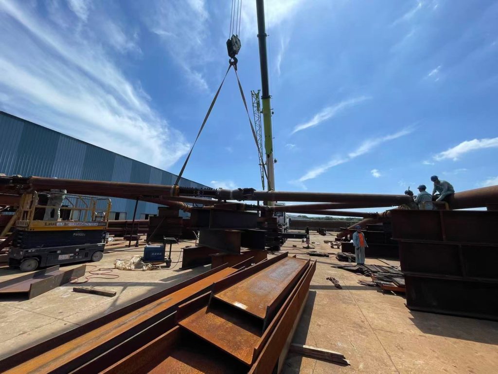 Large tubular steel module lifted by crane during trial assembly at HENZO